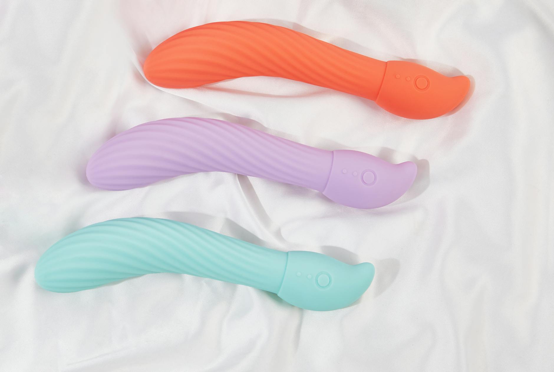 A teal vibrator on soft white silk fabric, symbolizing self-care and personal pleasure after heartbreak