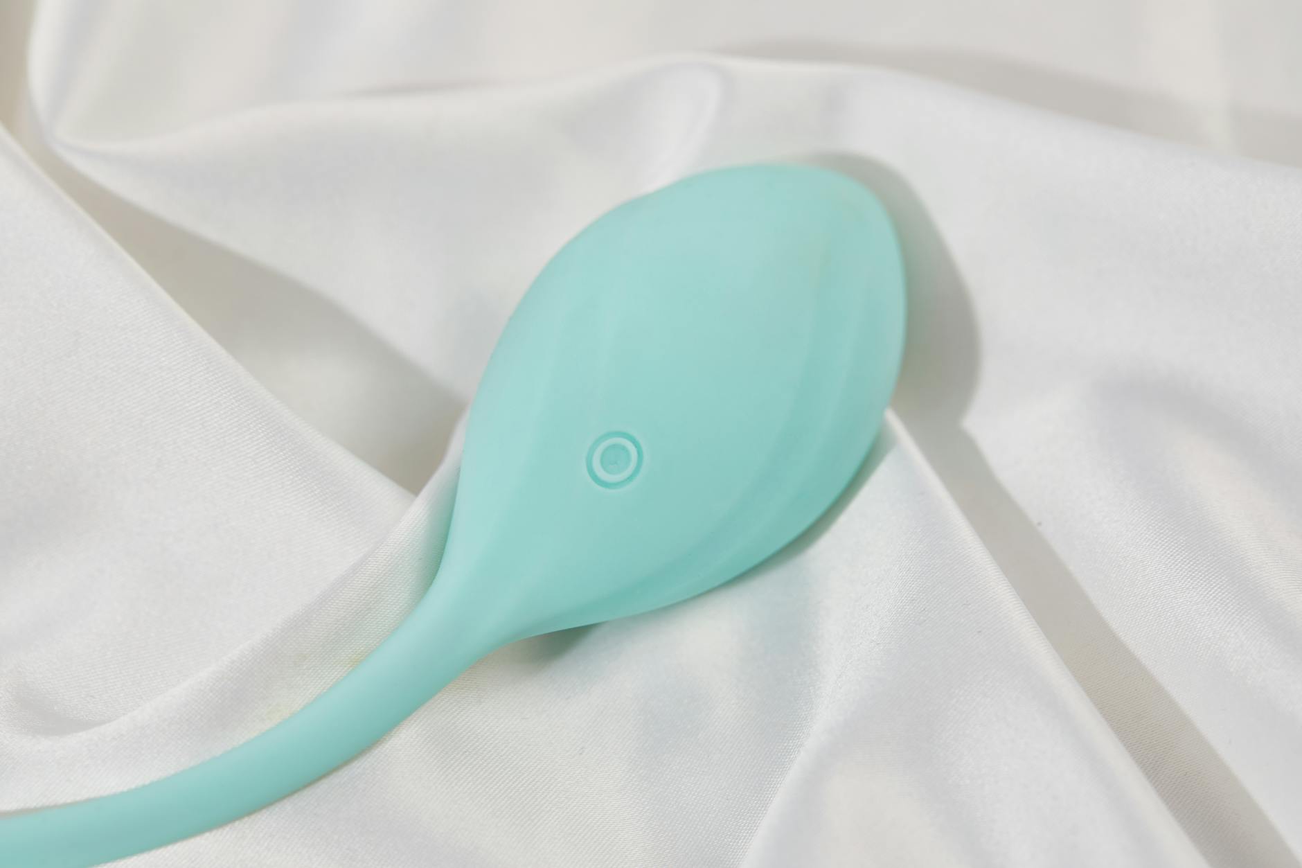 A teal silicone vibrator resting on white fabric, representing accessible self-pleasure during relationship stress