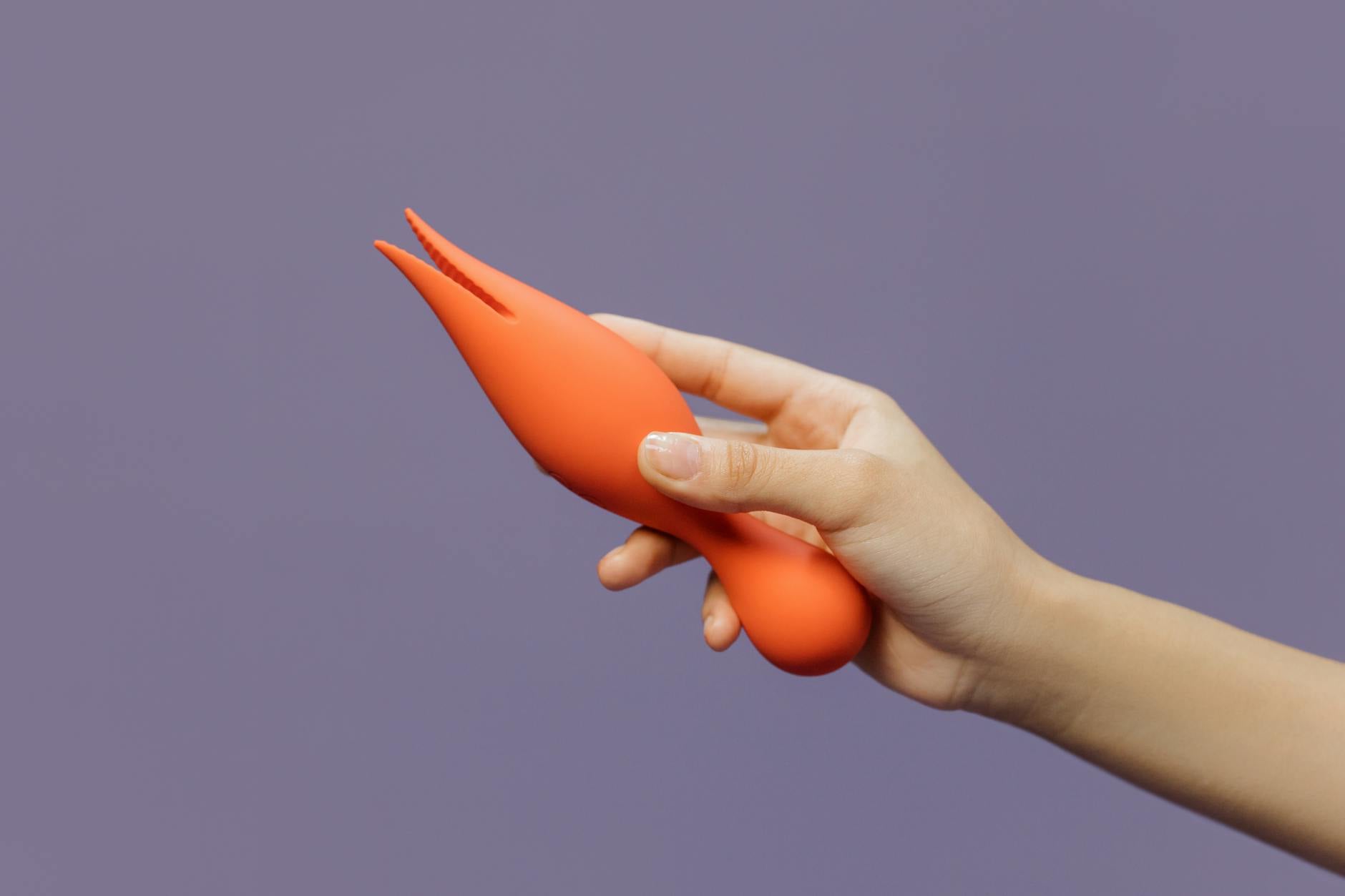 Hand holding a lemon-colored vibrator against a minimalist purple backdrop