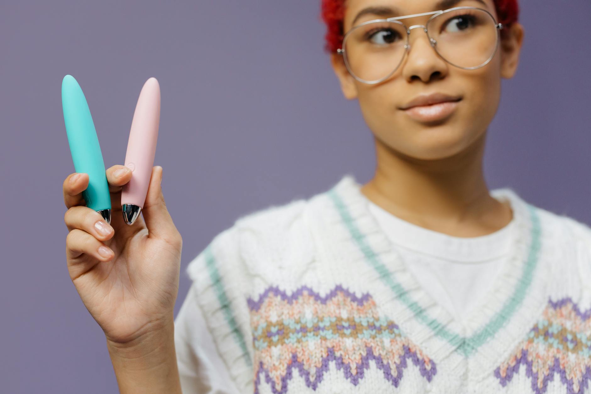 Woman holding a blue and pink clitoral vibrator, exploring pleasure for the first time