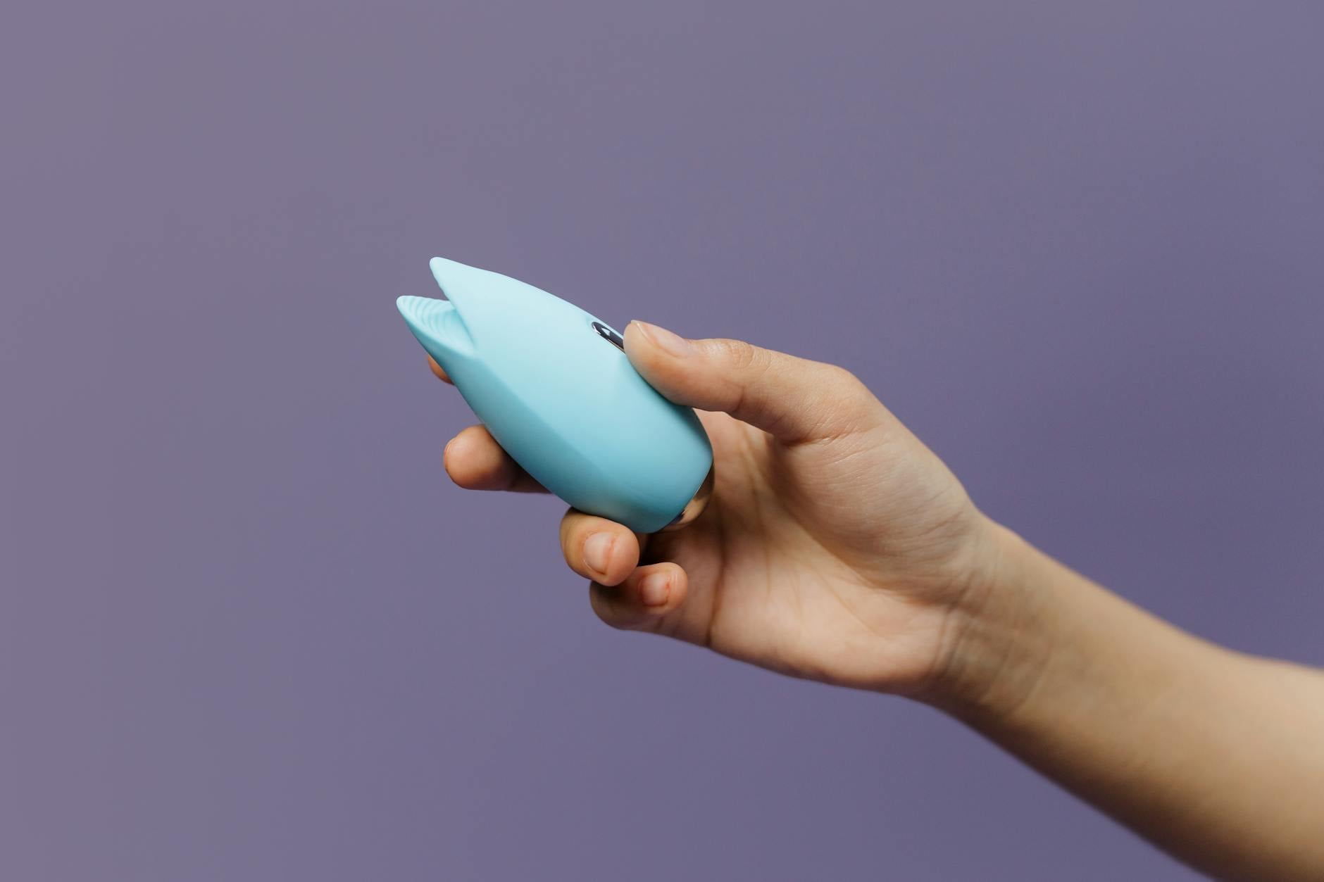 A blue silicone lemon vibrator held gently in hand, symbolizing mindful pleasure with sensitive skin