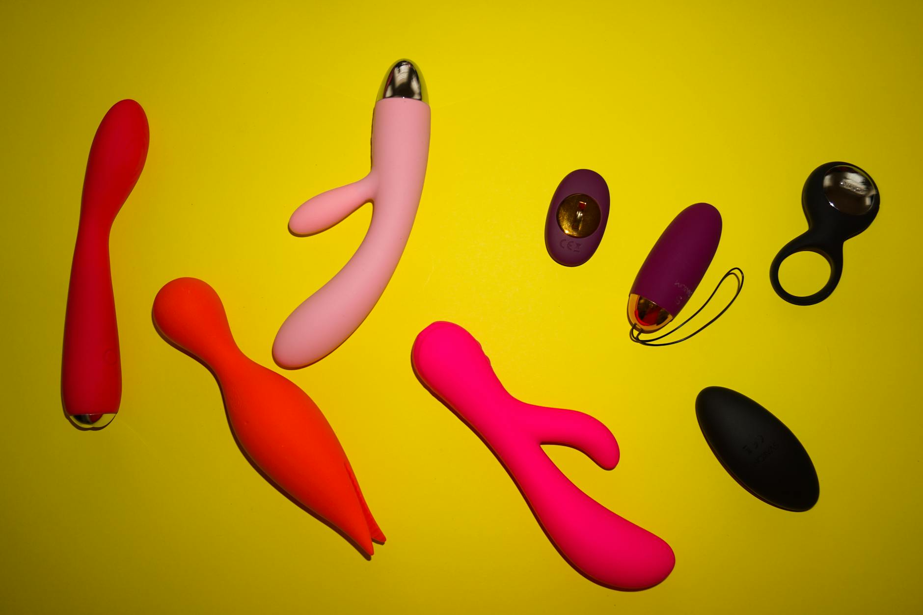Vibrant array of colorful sex toys on a yellow background, representing diverse sensation options