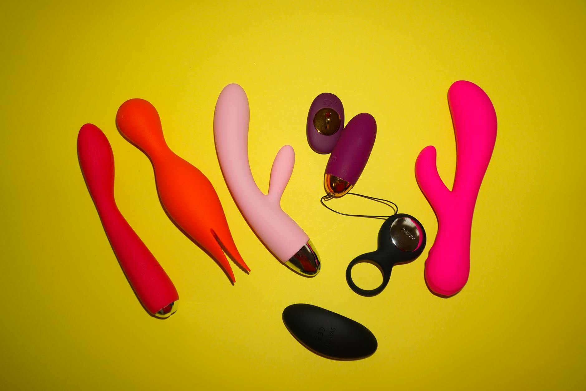 Bunte Sauger und Vibratoren auf leuchtend gelbem Hintergrund, die verschiedene Designs und Formen zeigen